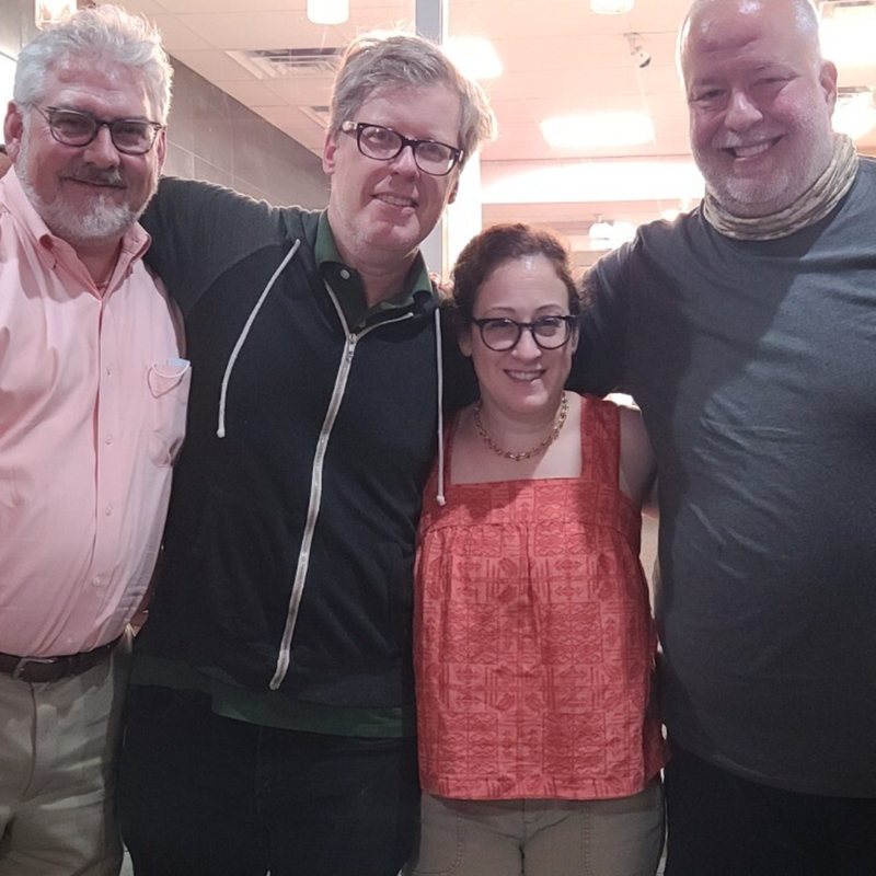 Chris and three friends standing arm in arm, smiling, at a restaurant meetup.